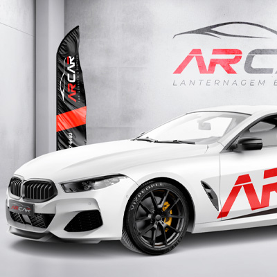 Carro esportivo branco com adesivagem da marca AR Car ao lado de um wind banner